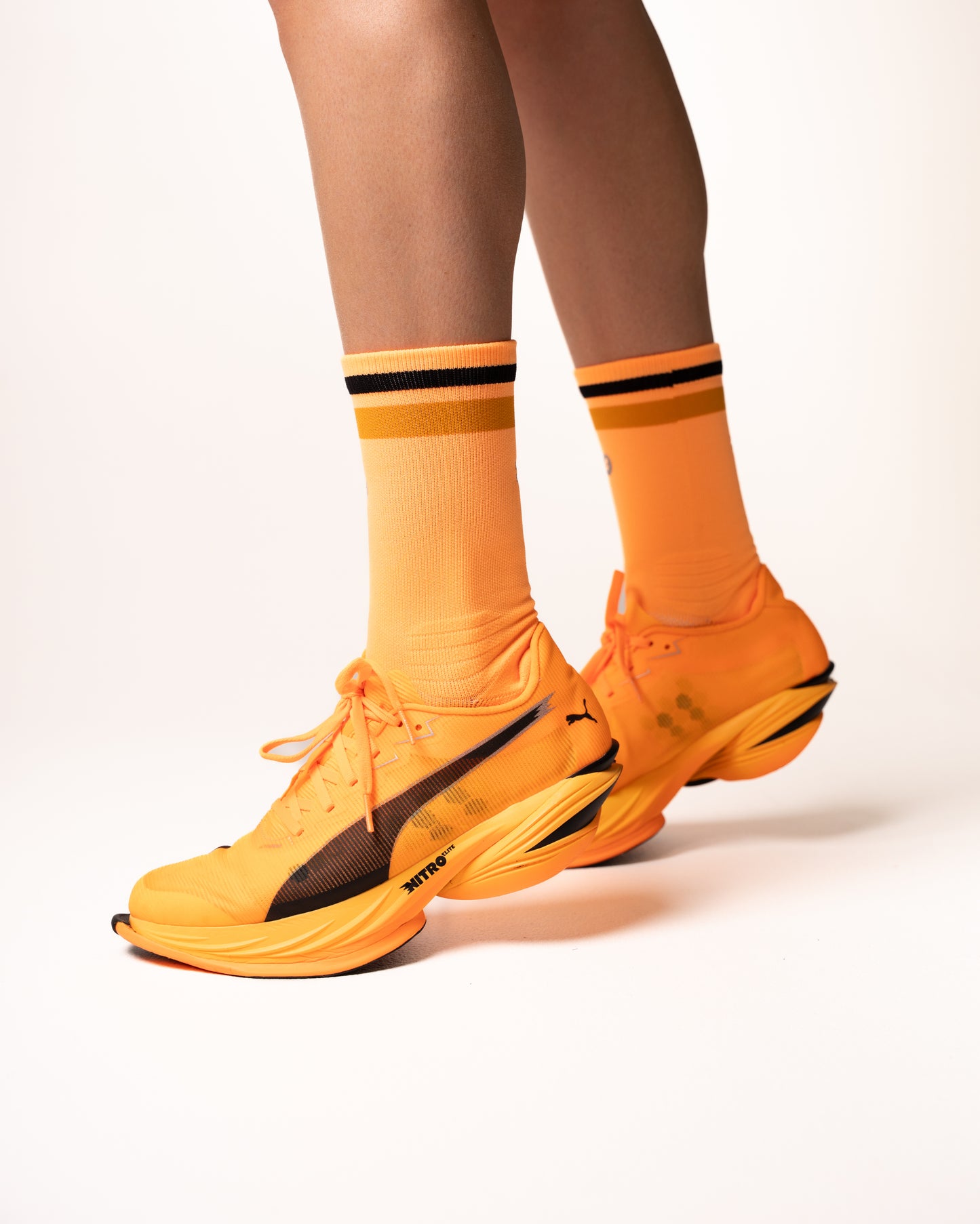 Orange running shoes with black accents on a white background